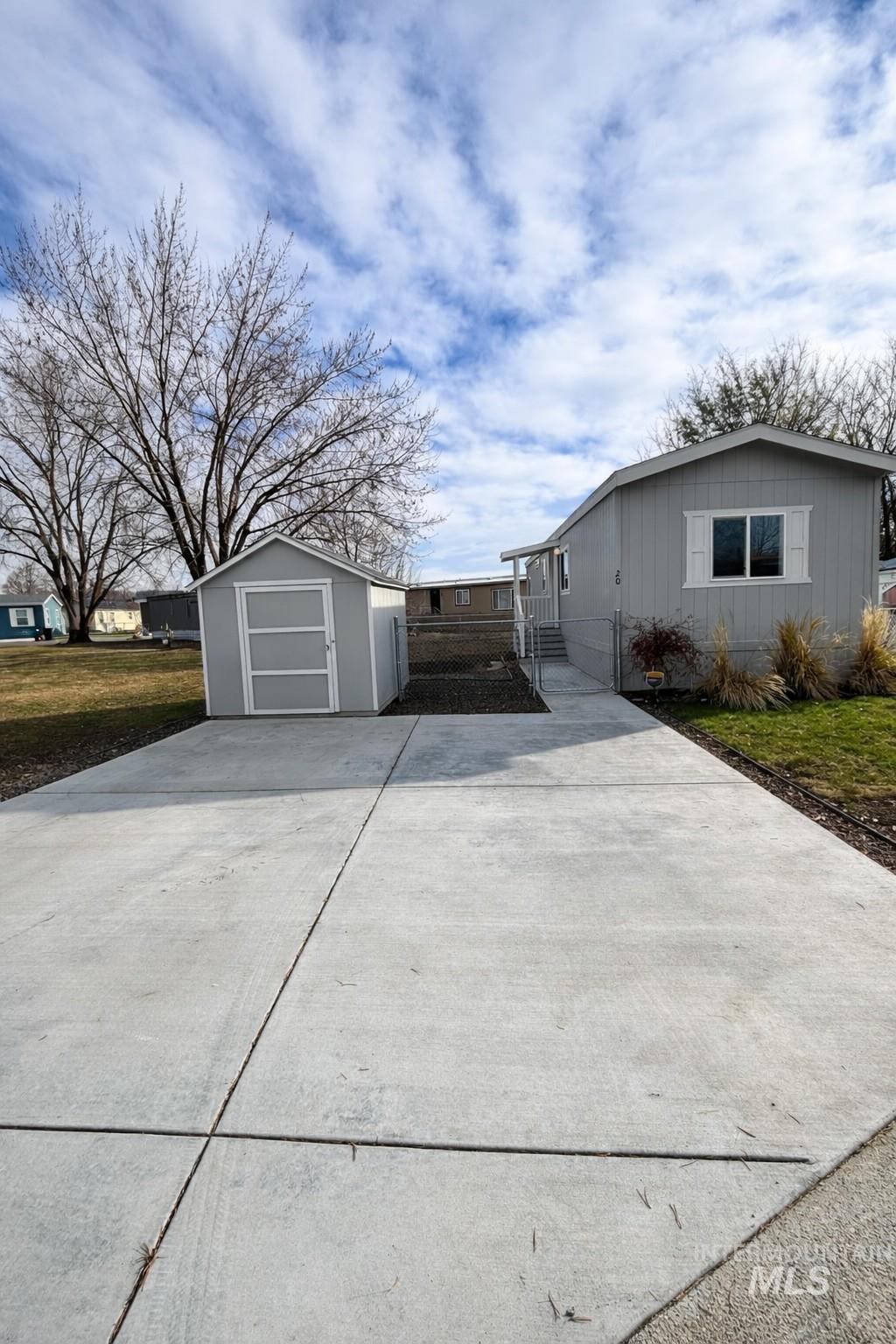 View of front of home featuring concrete driveway and a storage shed