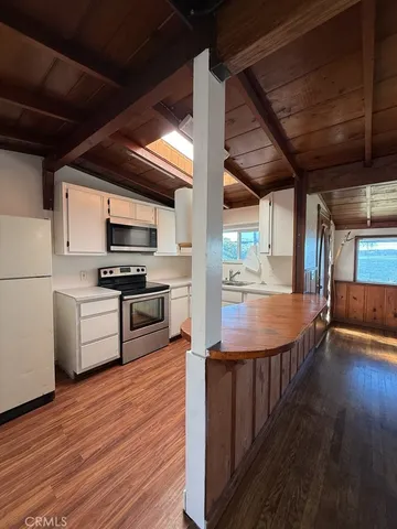 a kitchen with stainless steel appliances a kitchen island wooden floors and white cabinets