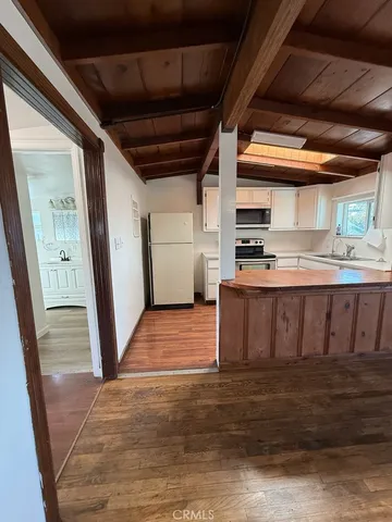 a utility room with stainless steel appliances wooden floors and wooden cabinets