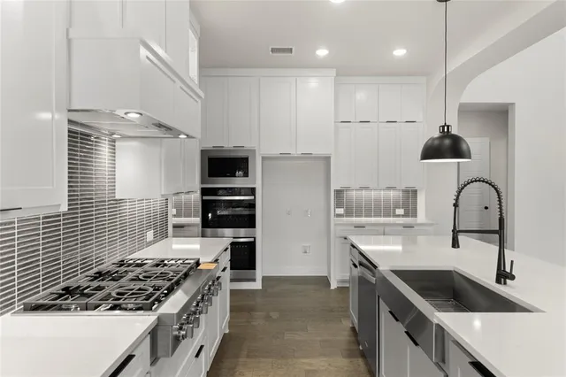 a kitchen with kitchen island stainless steel appliances a sink a stove and cabinets