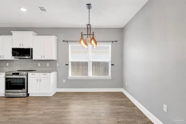 a view of an empty room with a kitchen and a window