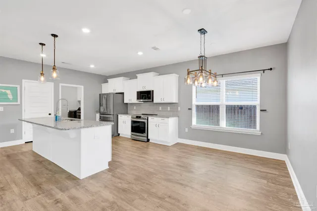 a view of kitchen with granite countertop stove top oven and cabinets