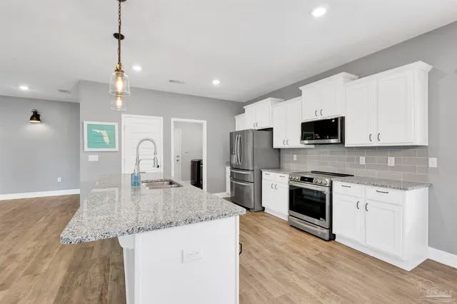 a kitchen with granite countertop a sink a counter top space stainless steel appliances and cabinets