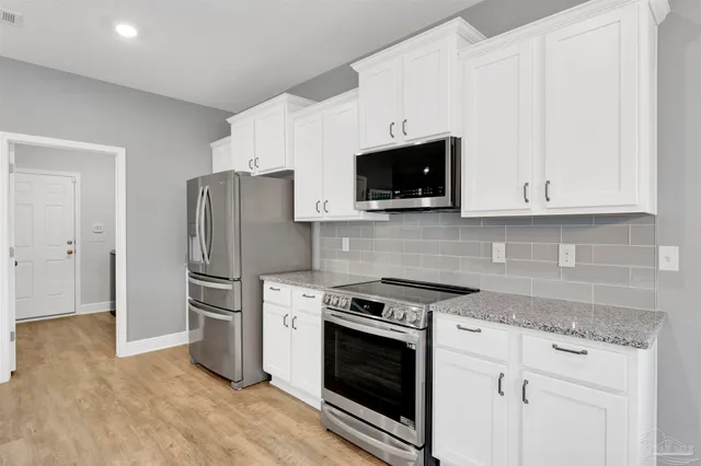 a kitchen with stainless steel appliances white cabinets a stove a microwave and a refrigerator