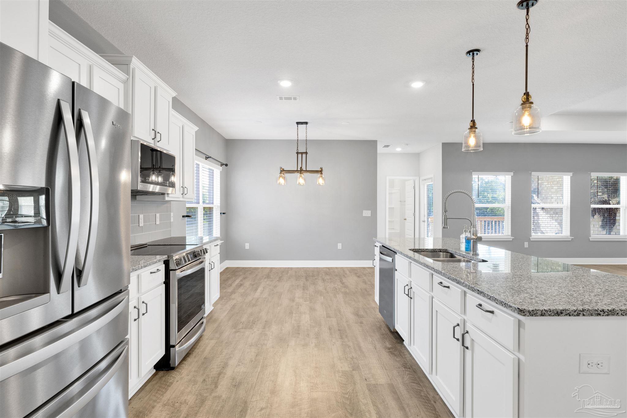 7907 Majestic Cypress Drive Milton, FL 32583 - Photo 17 of 36 a kitchen with stainless steel appliances granite countertop a sink stove and refrigerator