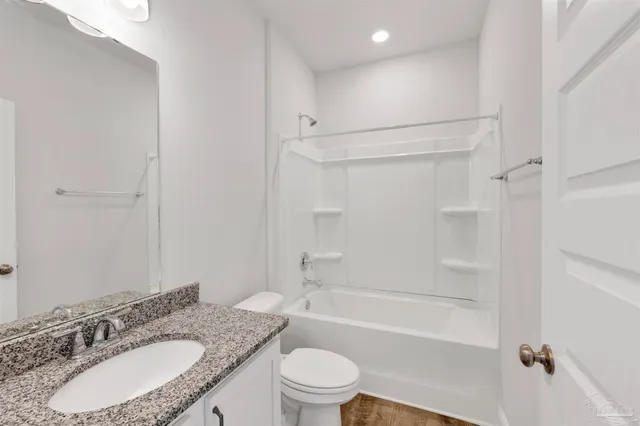 a bathroom with a granite countertop sink toilet mirror and shower