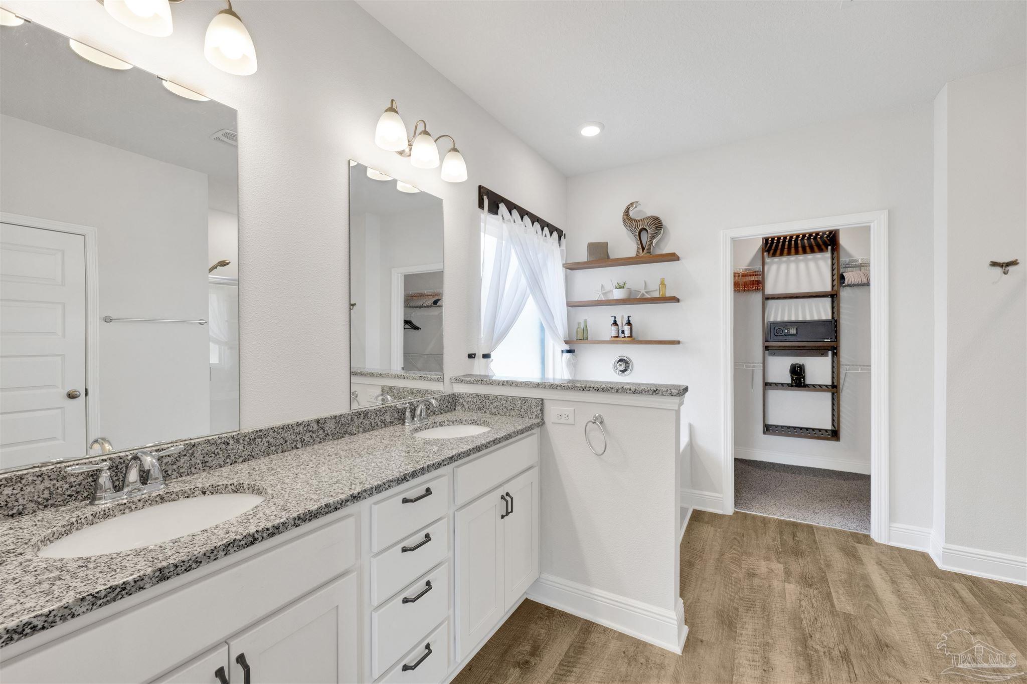 7907 Majestic Cypress Drive Milton, FL 32583 - Photo 22 of 36 a spacious bathroom with a granite countertop sink and a mirror