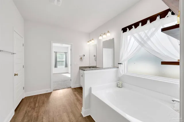 a large white kitchen with sink a refrigerator and white cabinets