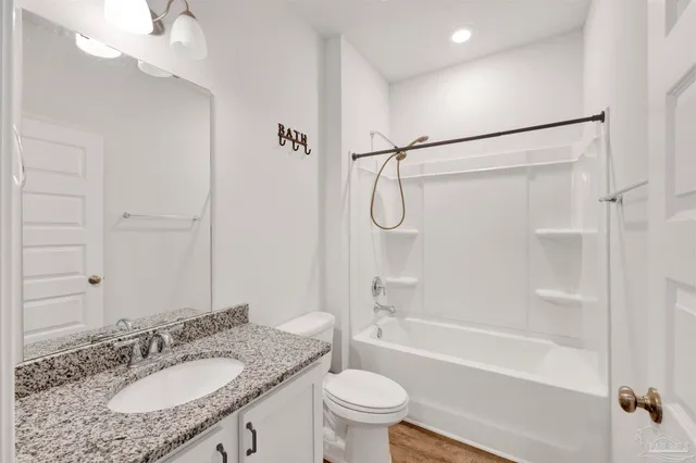 a bathroom with a granite countertop sink a toilet and shower