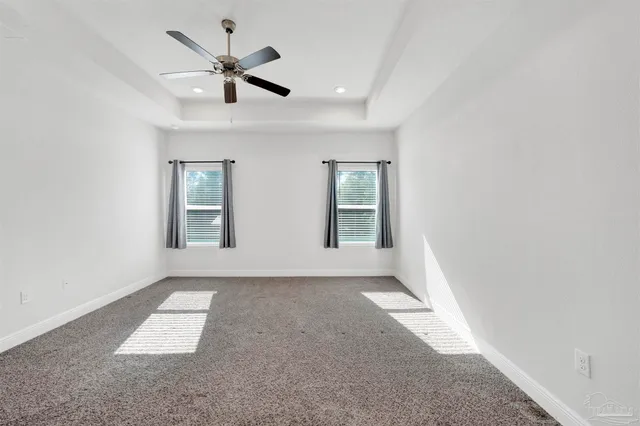 an empty room with windows and ceiling fan