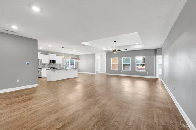 a view of an empty room with window and wooden floor