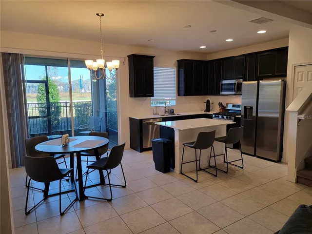 a kitchen with stainless steel appliances a table chairs refrigerator and microwave