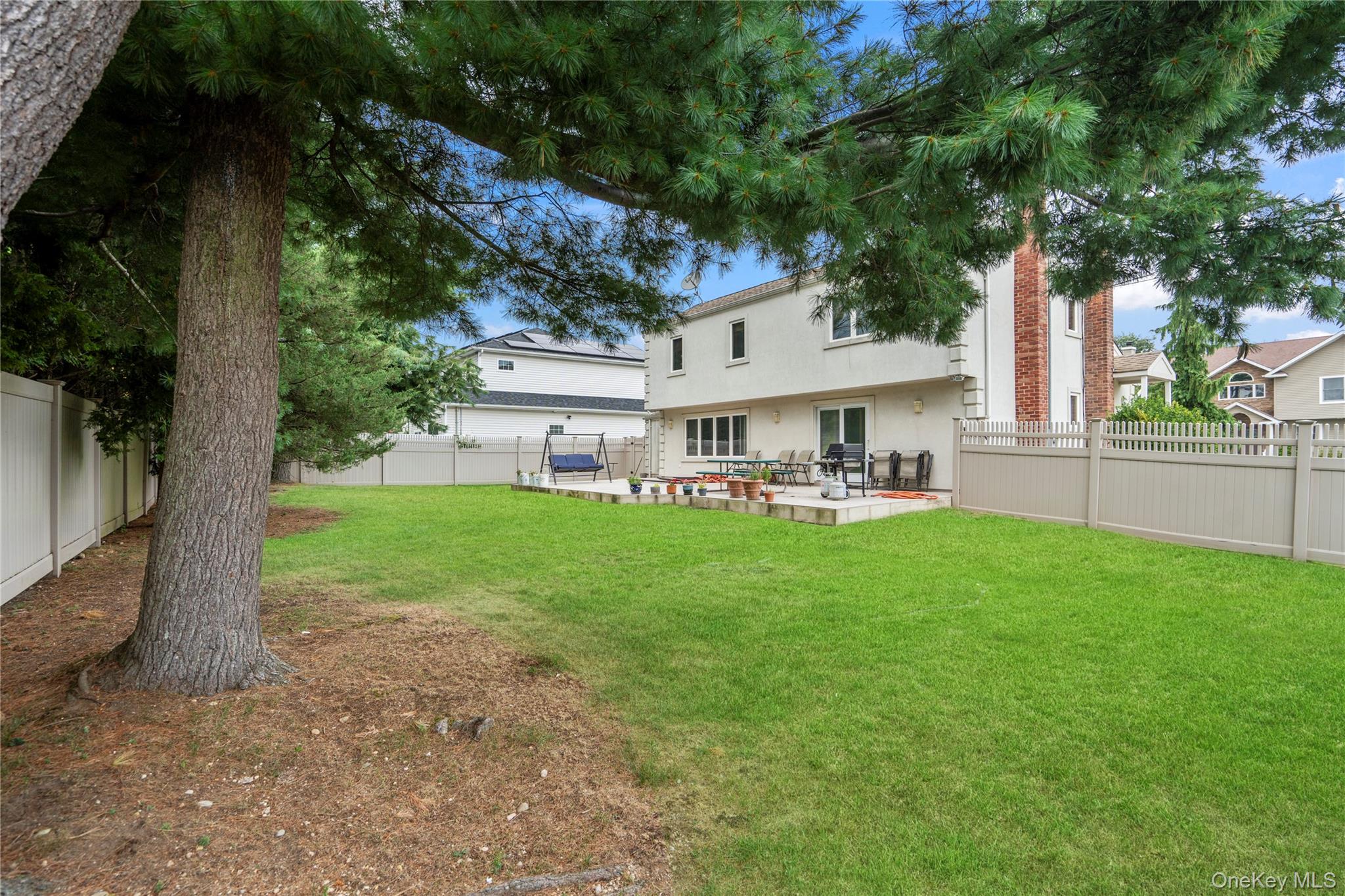 33 Shelter Hill Road Plainview, NY 11803 - Photo 26 of 34 Back of house featuring stucco siding, a patio area, and a fenced backyard