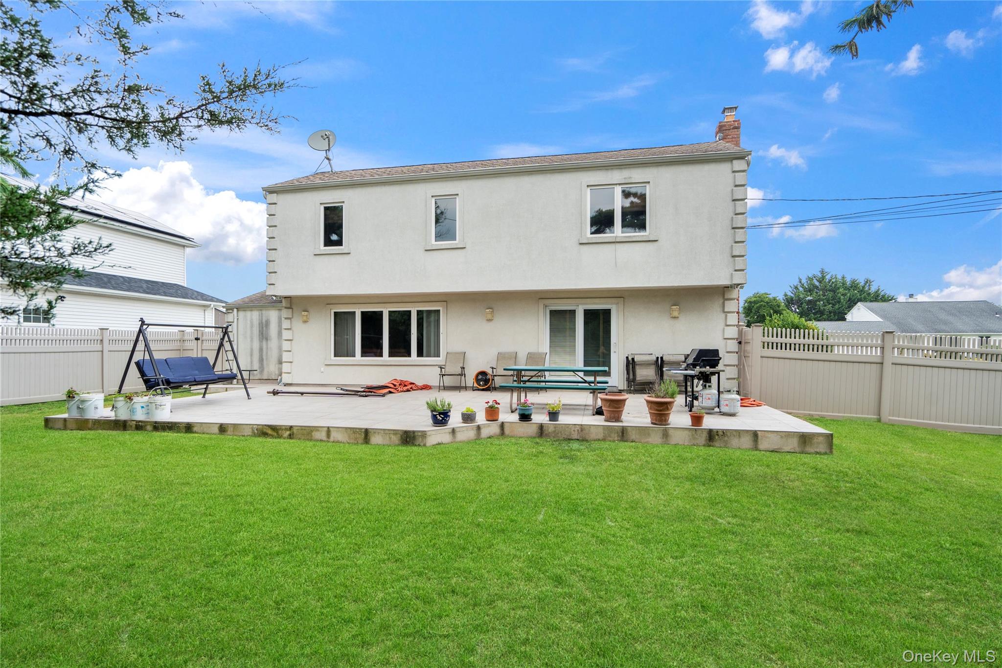 33 Shelter Hill Road Plainview, NY 11803 - Photo 27 of 34 Rear view of house featuring a fenced backyard, a chimney, stucco siding, and a patio area