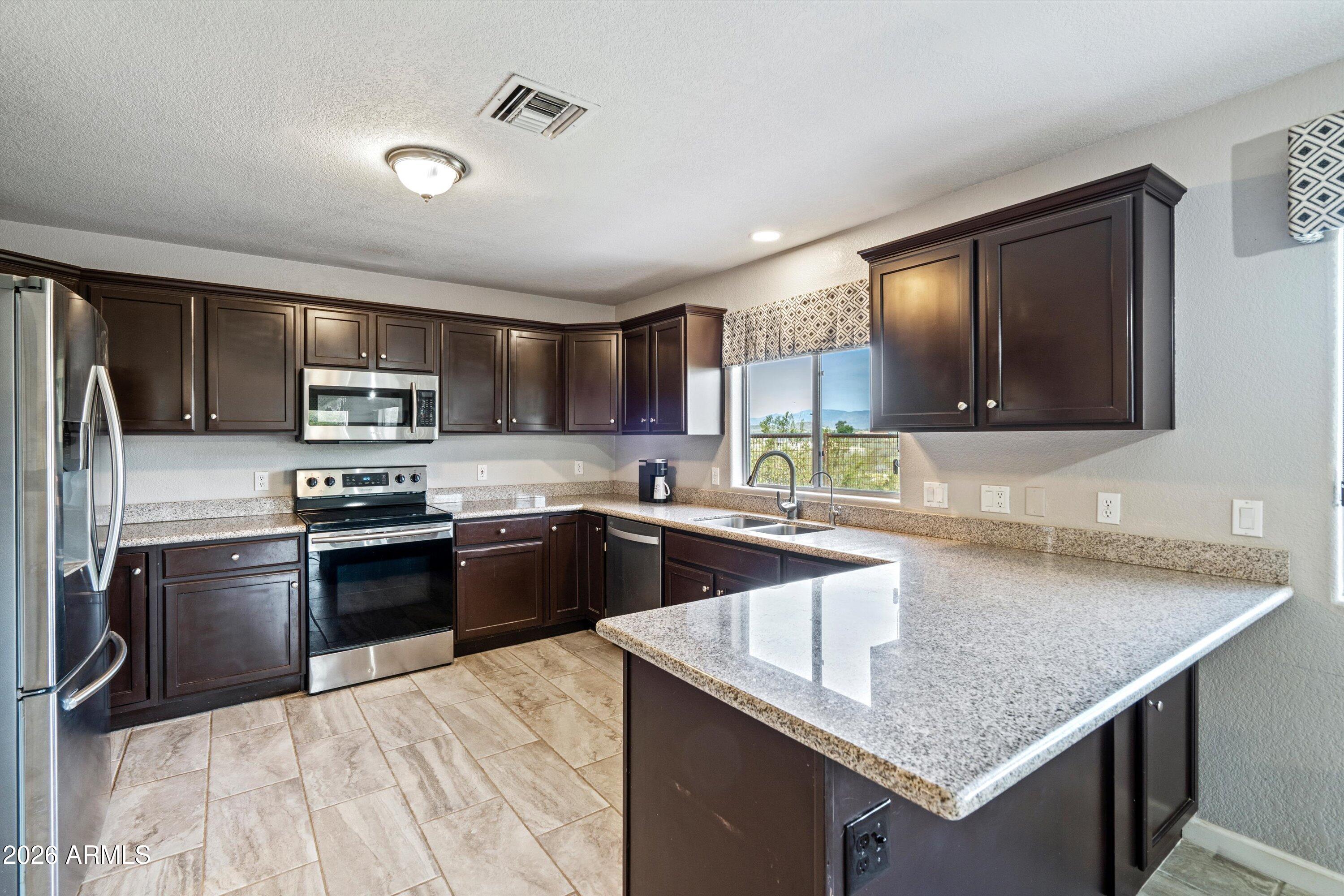 2316 West White Spar Road New River, AZ 85087 - Photo 10 of 40 a kitchen with stainless steel appliances granite countertop a sink dishwasher stove top oven and refrigerator