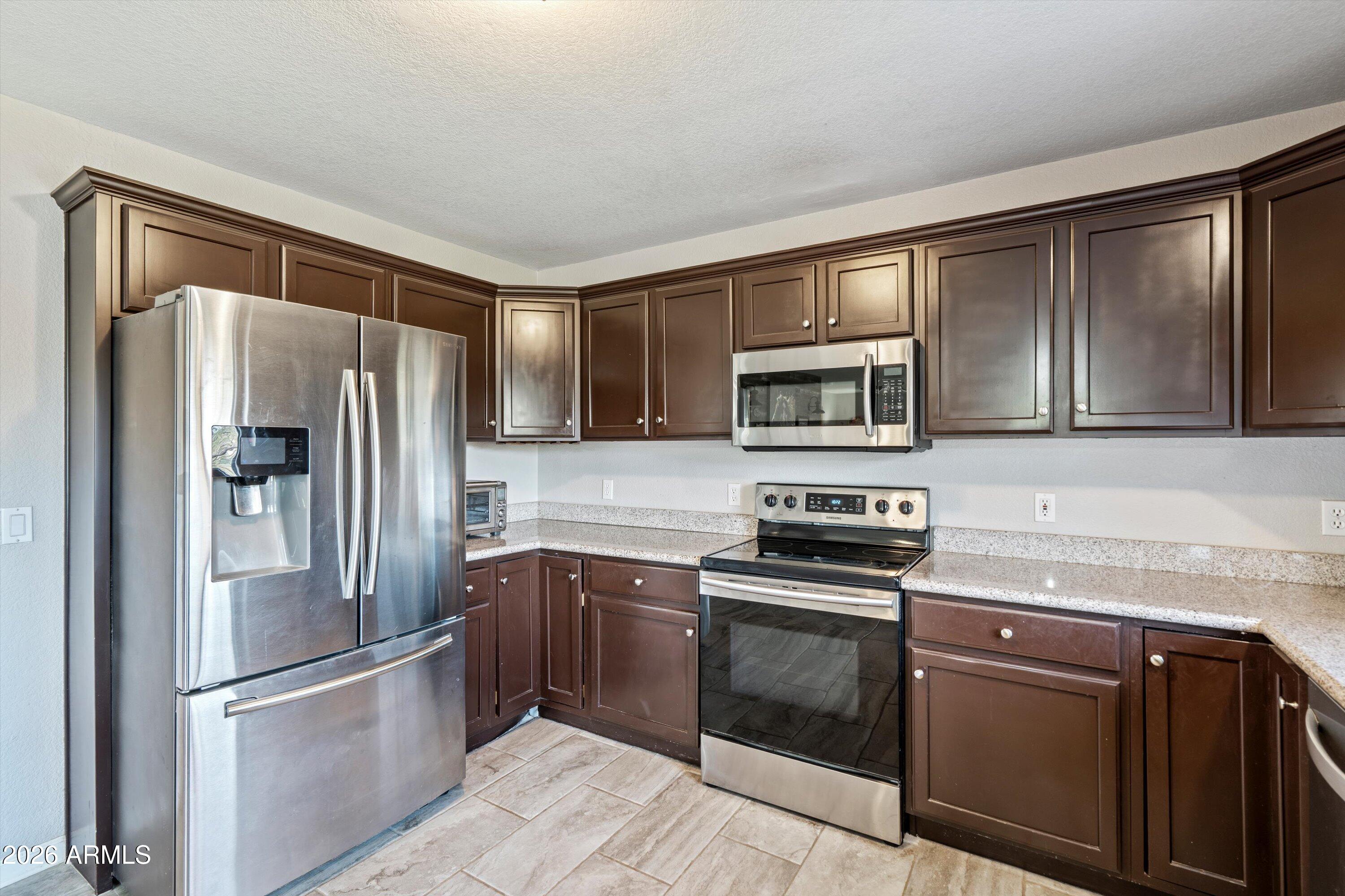 2316 West White Spar Road New River, AZ 85087 - Photo 12 of 40 a kitchen with stainless steel appliances granite countertop a refrigerator stove and sink