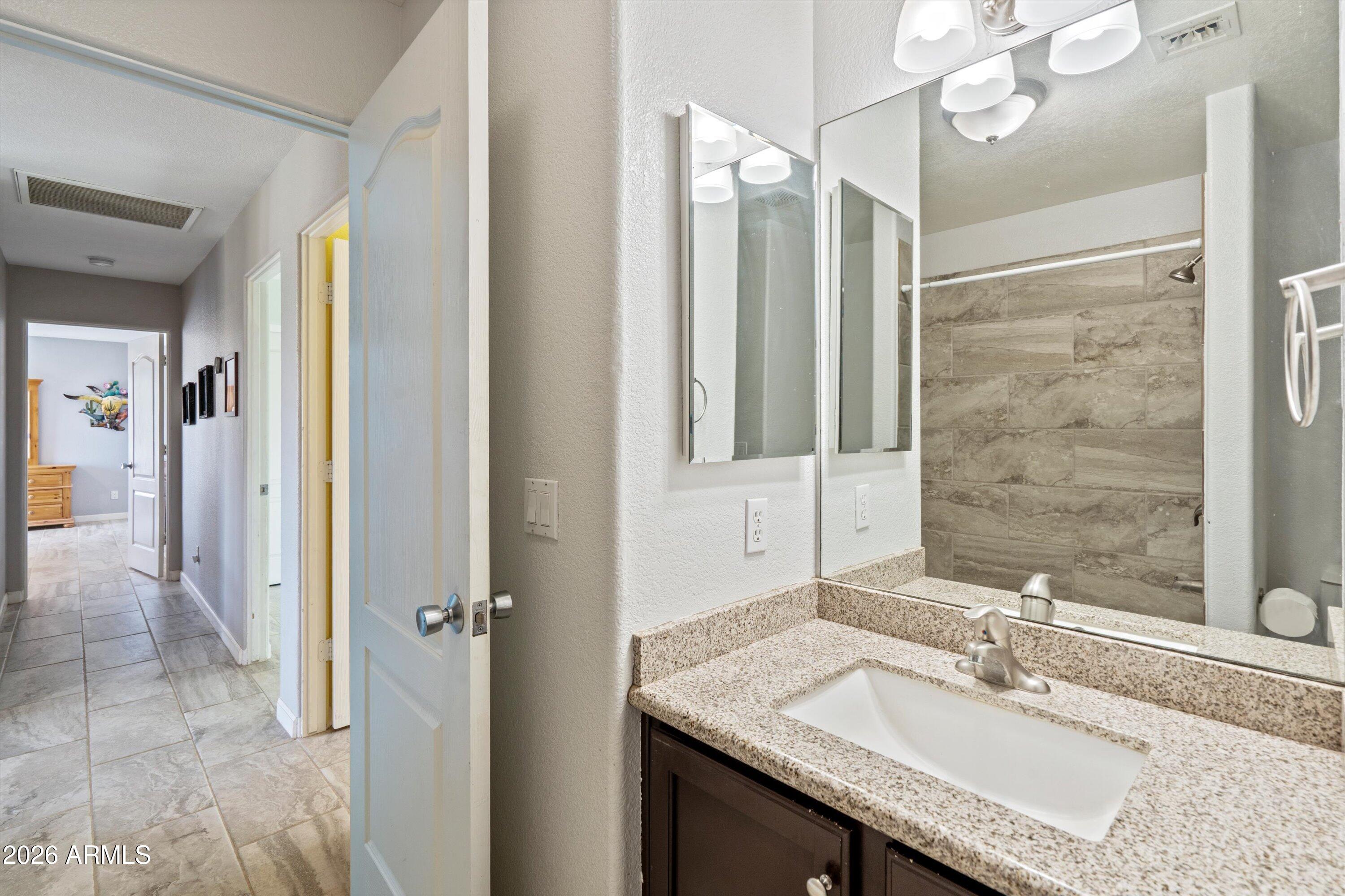 2316 West White Spar Road New River, AZ 85087 - Photo 22 of 40 a bathroom with a granite countertop sink and a mirror