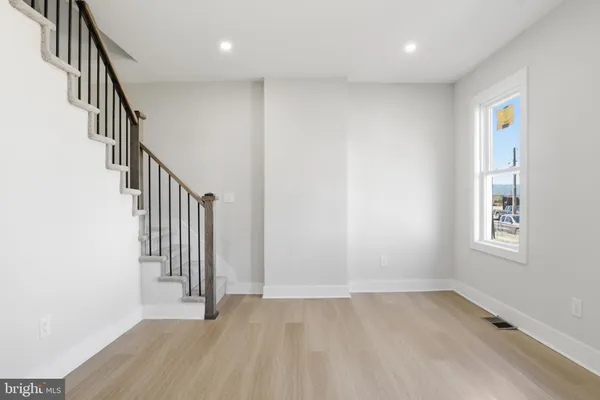 an entryway of a room with wooden floor and stairs