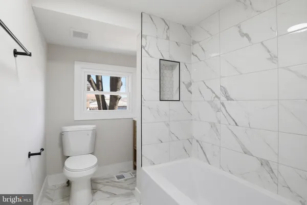 a white toilet sitting next to a white bath tub