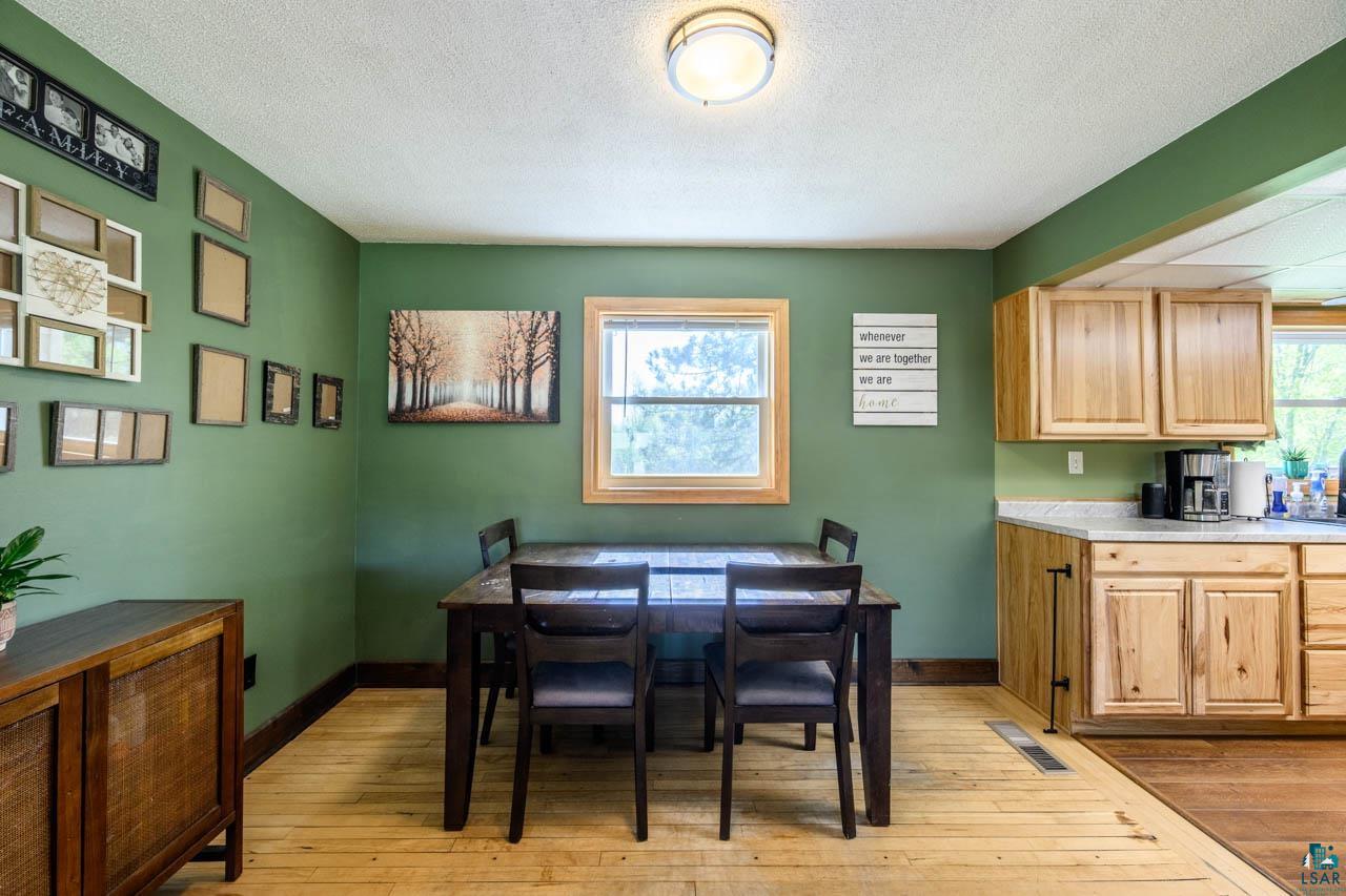 2581 O'Rourke Road Hibbing, MN 55746 - Photo 6 of 61 Dining area featuring light wood-finish flooring, a window with natural wood trim, and a ceiling-mounted light fixture