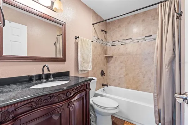 a bathroom with a granite countertop sink a mirror a bathtub and a toilet