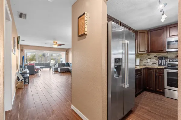 a kitchen with a refrigerator a stove top oven a sink and dining table with wooden floor