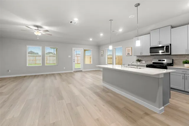 a large kitchen with kitchen island granite countertop a stove a sink a window and white cabinets