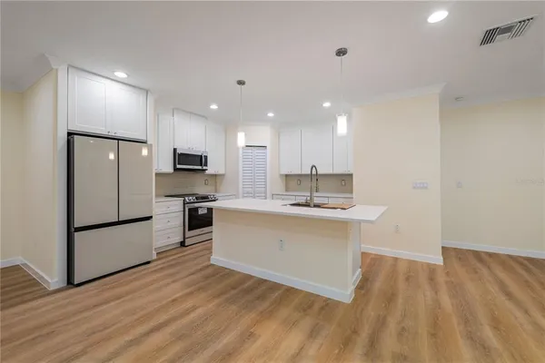 a kitchen with a sink stainless steel appliances and wooden floor