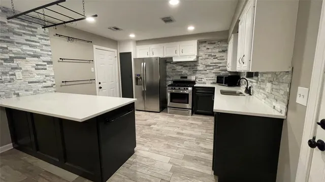 a kitchen with a refrigerator sink and cabinets
