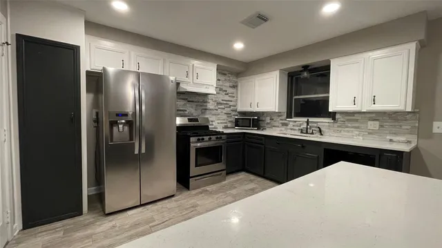 a bathroom with a granite countertop bathtub a sink and a wooden floor