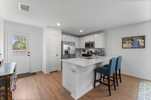 a kitchen with stainless steel appliances a refrigerator a stove a sink dishwasher and a dining table with wooden floor