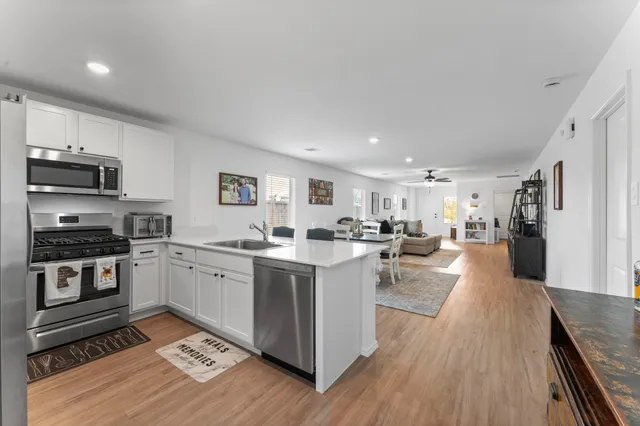 a kitchen with stainless steel appliances granite countertop a refrigerator a stove top oven a sink dishwasher and white cabinets next to a window