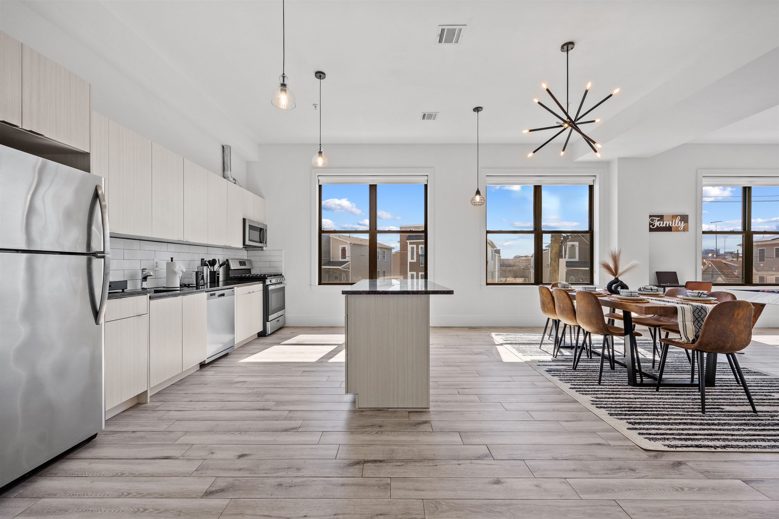 a kitchen with stainless steel appliances granite countertop a refrigerator a stove top oven a sink dishwasher a dining table and chairs with wooden floor