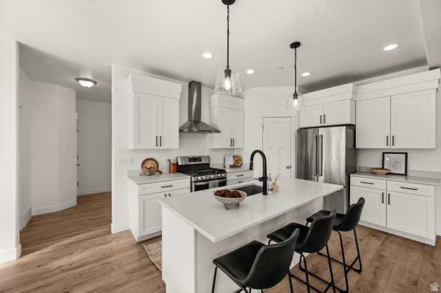 14728 South Canyon Pointe Road Draper, UT 84020 - Photo 10 of 35 Spacious kitchen featuring white cabinetry, stainless steel appliances, a center island with seating, pendant lighting, and wood-finish flooring