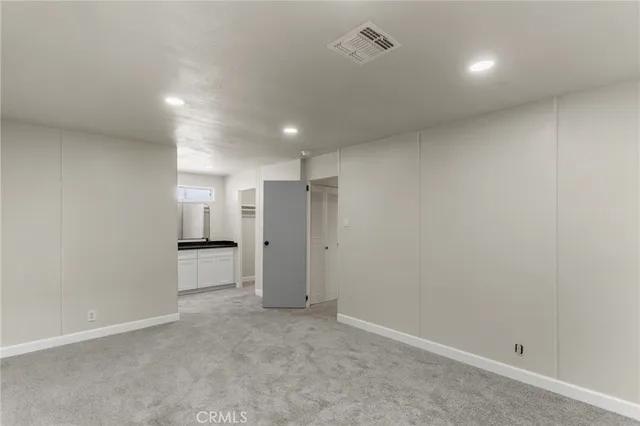 an empty room with a cabinet and a refrigerator