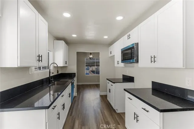 a kitchen with granite countertop a sink a counter top space stainless steel appliances and cabinets