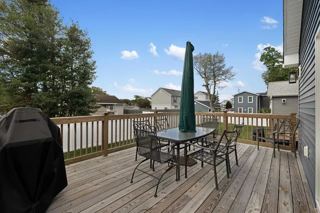 a view of a roof deck with table and chairs a barbeque with wooden floor and fence