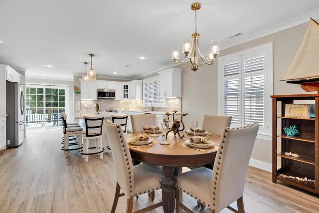 a large white kitchen with stainless steel appliances granite countertop a stove a sink a oven and a dining table with wooden floor