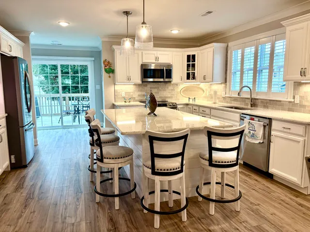 a kitchen with stainless steel appliances granite countertop a stove a sink dishwasher a dining table and chairs with wooden floor