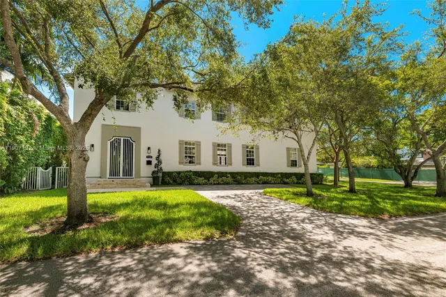 a view of a white house with a big yard and large trees