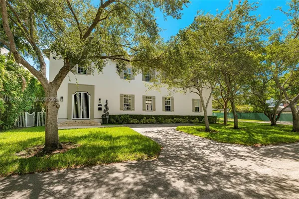 a view of house with a big yard and large trees