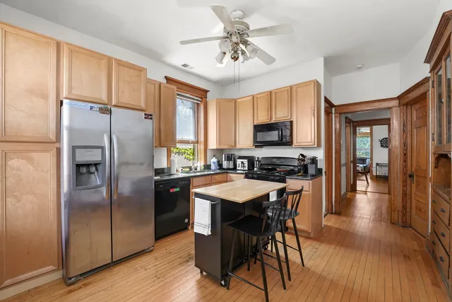 a kitchen with stainless steel appliances granite countertop a refrigerator a stove a sink a dining table and chairs with wooden floor