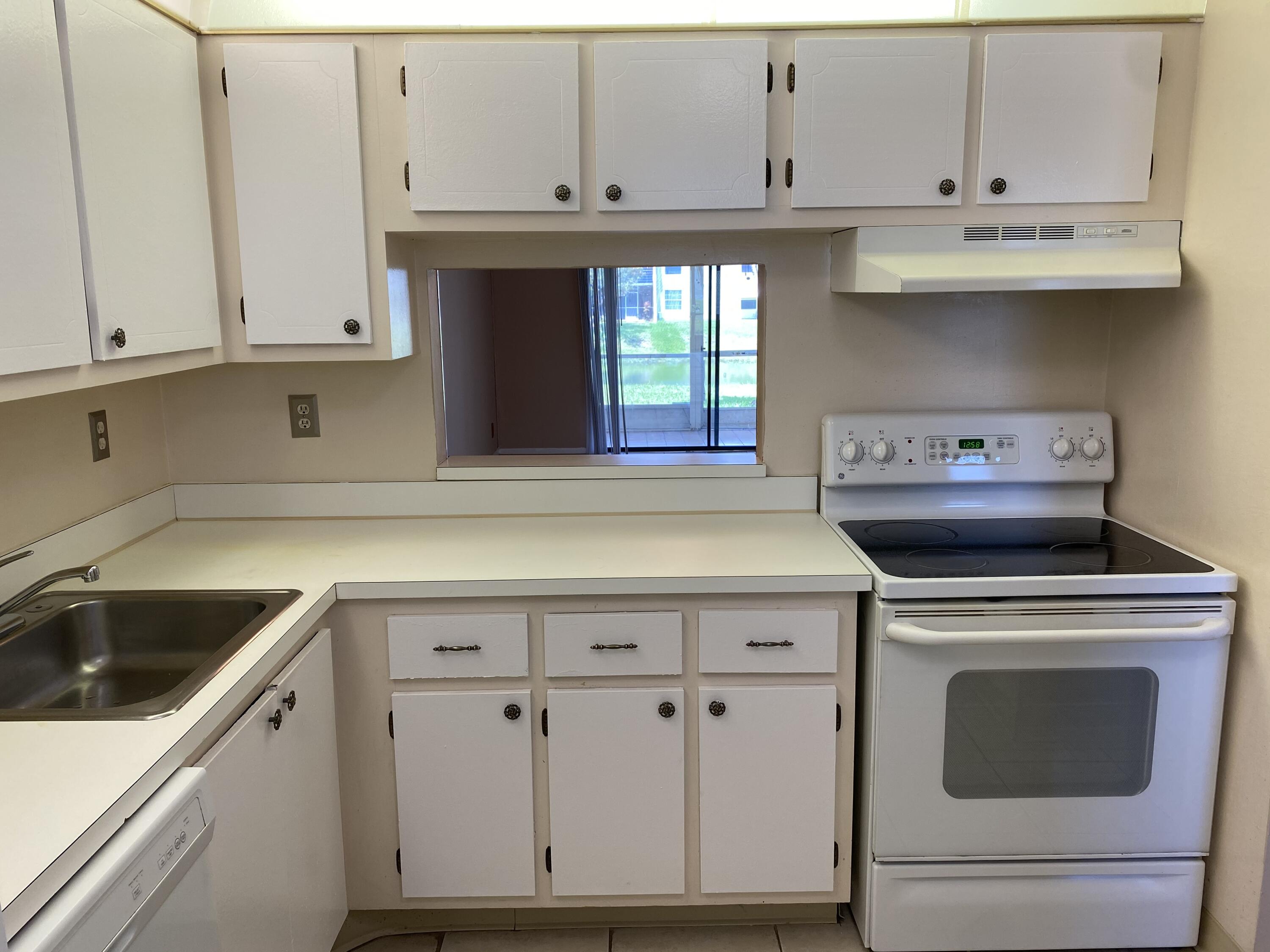 2500 Fiore Way, Unit 1110 Delray Beach, FL 33445 - Photo 2 of 12 a kitchen with granite countertop white cabinets and white appliances