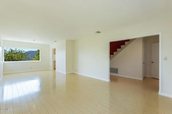 an empty room with wooden floor cabinet and windows