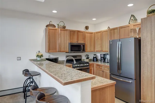 a kitchen with granite countertop a refrigerator and a stove top oven