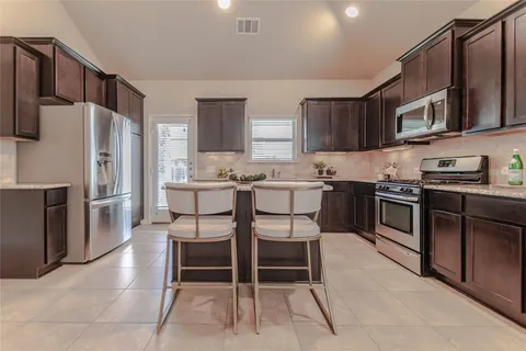 a kitchen with stainless steel appliances granite countertop a stove a sink refrigerator and a microwave