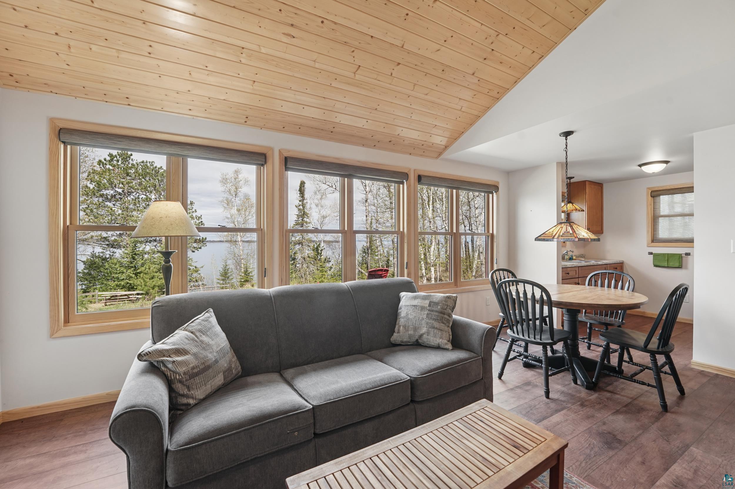 89095 West Romans Point Road Herbster, WI 54844 - Photo 14 of 30 Spacious living area featuring expansive windows with natural wood trim, wood-finish flooring, and a natural wood-paneled ceiling