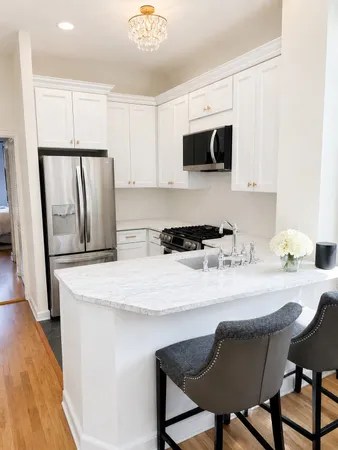 a kitchen with stainless steel appliances granite countertop a stove a refrigerator a microwave and white cabinets