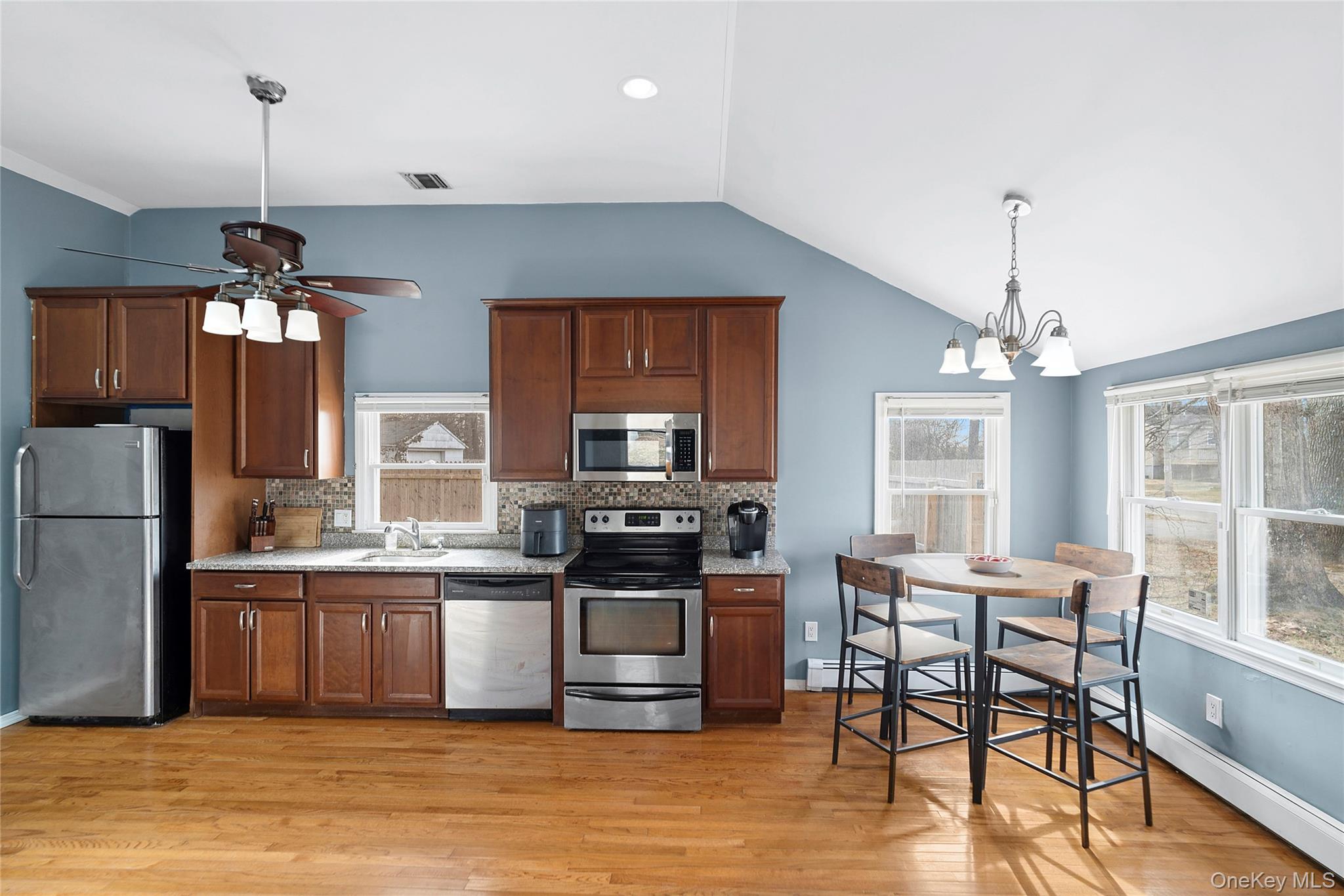 69 Locust Drive Mastic Beach, NY 11951 - Photo 5 of 13 a kitchen with stainless steel appliances a dining table chairs stove and refrigerator