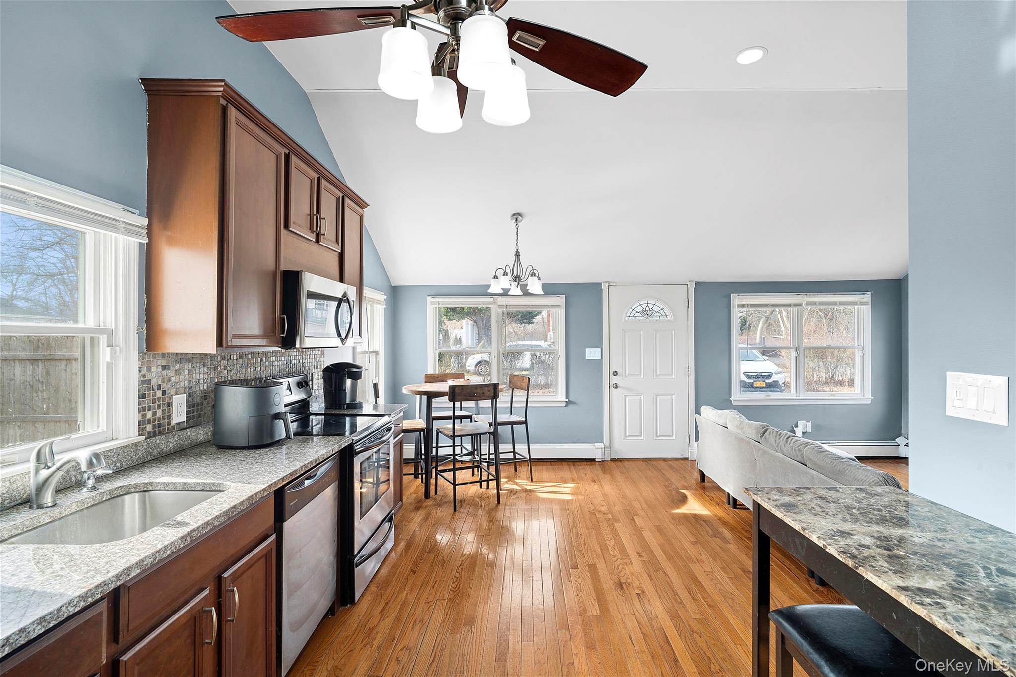 69 Locust Drive Mastic Beach, NY 11951 - Photo 6 of 13 a open kitchen with granite countertop a sink dishwasher a stove and a dining table with wooden floor